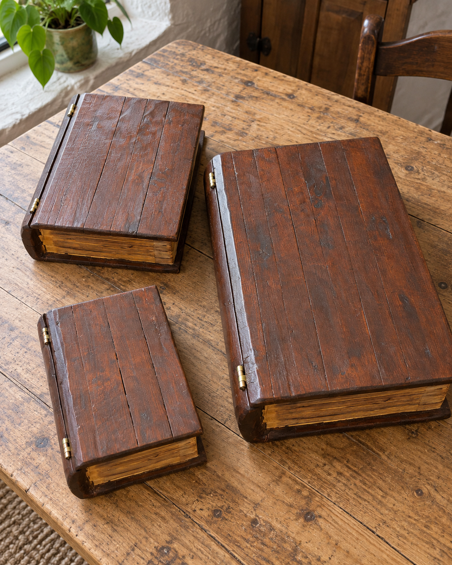Embergarth Complete Set of three decorative wooden storage boxes shaped like books, lying flat on a wooden table with gold-toned spine hinges visible.